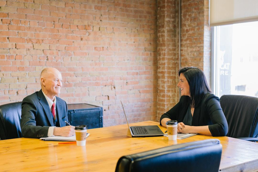 Two professionals in an office conference room gathered around a table, discussing and collaborating on customization and flexibility in opportunity tracking